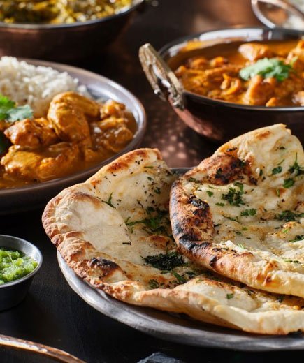 Fresh naan bread served with Indian curry at an Indian Restaurant in Brighouse - Swadish